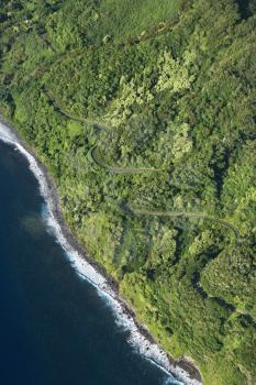 Royalty Free Photo of an Aerial View of a Winding Road Along a Coastline Through a Lush Green Forest in Maui, Hawaii