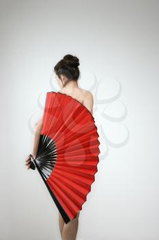 Royalty Free Photo of a Nude Woman Holding a Fan Covering Her Back