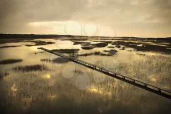 Royalty Free Photo of a Scenic Wooden Walkway Stretching Over Wetlands at a Sunset on Bald Head Island, North Carolina