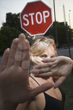 Royalty Free Photo of a Woman Holding Up Her Hands in Front of a Stop Sign
