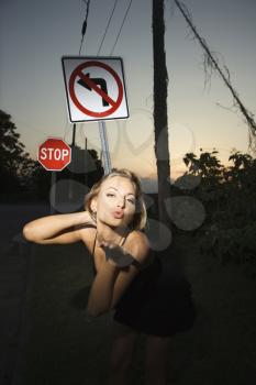 Royalty Free Photo of a Woman Blowing a Kiss Beside a No Left Turn Sign