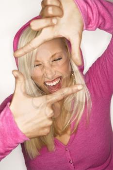 Royalty Free Photo of a Blonde Woman Wearing Fuchsia Holding Hands Up to Make a Frame Around Her Face