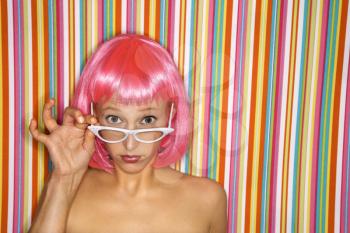 Royalty Free Photo of a Young Woman Wearing a Pink Wig Against a Striped Background Making a Sassy Expression