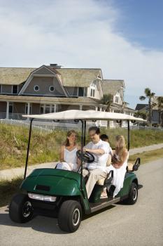 Royalty Free Photo of a Family Driving a Golf Cart Down the Street