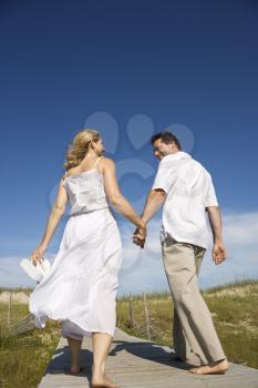Royalty Free Photo of a Couple Holding Hands Walking Down the Beach Access Path