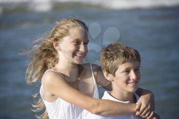 Royalty Free Photo of a Girl With Her Arms Around a Boy on a Beach