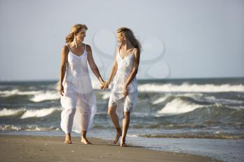Royalty Free Photo of a Mother and Preteen Daughter Walking on a Beach Holding Hands