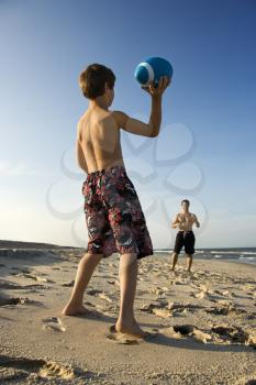 Caucasian pre-teen boy throwing football to mid-adult male.