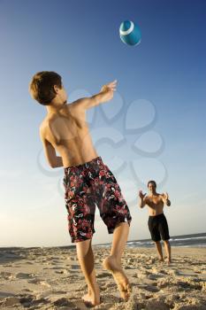 Caucasian pre-teen boy throwing football to mid-adult male.