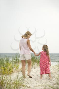 Royalty Free Photo of a Woman Walking and Holding Hands With a Female Child on a Beach