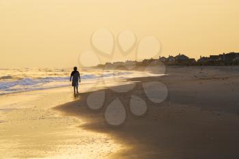 Royalty Free Photo of a Boy Walking on a Beach at Sunset