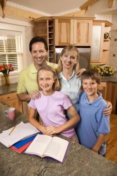 Royalty Free Photo of a Family of Four Standing in a Kitchen Posing with Homework on the Counter