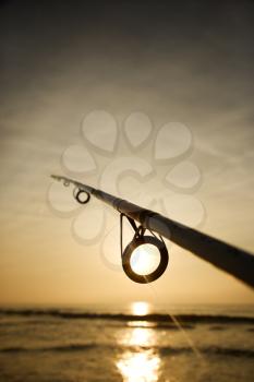 Royalty Free Photo of a Fishing Pole Against Ocean at Sunset