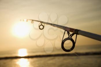 Royalty Free Photo of a Fishing Pole Against Ocean at Sunset