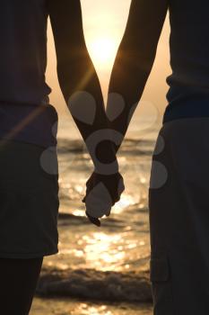 Royalty Free Photo of a Mother and Daughter Holding Hands on the Beach at Sunset