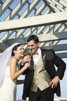 Caucasian mid-adult bride and groom drinking champagne.