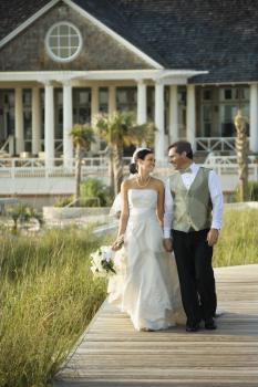 Royalty Free Photo of a Groom and Bride Walking Down a Beach Walkway