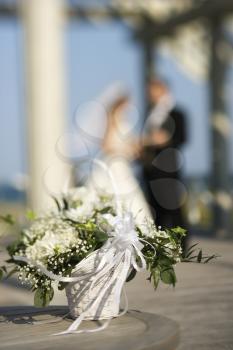 Royalty Free Photo of a Flower Basket With a Bride and Groom Blurred in the Background
