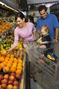 Royalty Free Photo of Parents Grocery Shopping for Fruit With Their Toddler Son