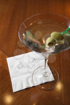 Royalty Free Photo of a Martini and a Note on a Napkin Reading 'Get Lost.'