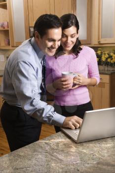 Royalty Free Photo of a Couple Looking at Their Laptop in the Kitchen