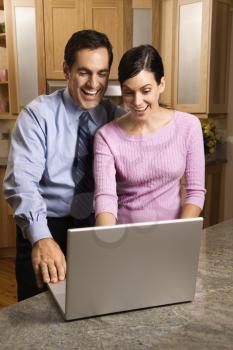 Royalty Free Photo of a Couple Standing in a Kitchen Looking at a Laptop