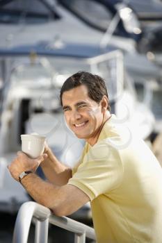 Royalty Free Photo of a Man Holding a Coffee Cup at a Harbor 