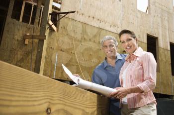 Royalty Free Photo of a Couple Holding Blueprints and Smiling