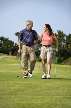 Royalty Free Photo of a Man and Woman Walking on a Golf Course Talking to Each Other