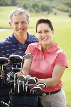 Royalty Free Photo of a Man and Woman With Golf Clubs Smiling