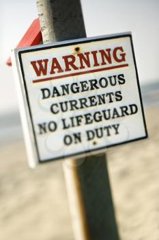 Royalty Free Photo of a Warning Sign on a Post at the Beach