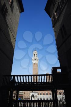 Royalty Free Photo of Torre del Mangia Tower Framed by Buildings in an Alley
