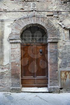 Royalty Free Photo of a Wooden Door With Brick Archway, Italy