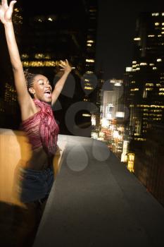 Royalty Free Photo of a Woman Jumping and Screaming With Excitement on Patio in New York City, New York at Night