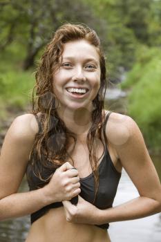 Royalty Free Photo of a Woman Standing in a Stream Wringing Water Out of Her Shirt Smiling 