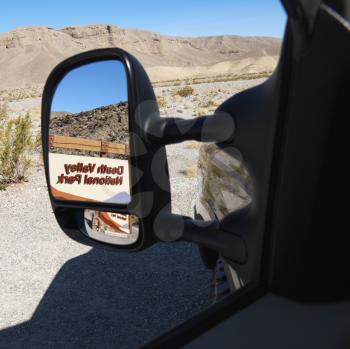 Royalty Free Photo of the Death Valley National Park Entrance Sign Reflected in the Side View Vehicle Mirror