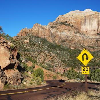 Royalty Free Photo of a Curve Caution Sign on a Two Lane Road Winding Through the Rocky Desert Cliffs in Zion National Park, Utah