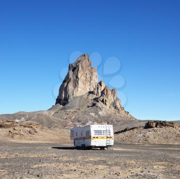 Royalty Free Photo of an RV Traveling Toward a Rock Formation in the Desert of Monument Valley, Utah