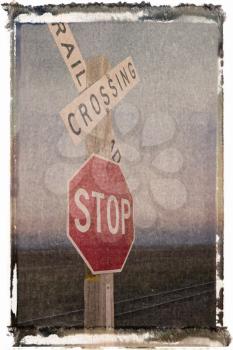 Royalty Free Photo of a Polaroid Transfer of a Railroad Crossing and Stop Signs Beside Railroad Tracks in a Rural Setting