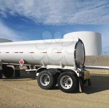 Royalty Free Photo of a Side View of a Fuel Tanker Truck With a Fuel Tank Farm in a Background