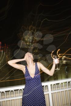 Royalty Free Photo of a Woman Smiling and Drinking at Night With Blurred Lights