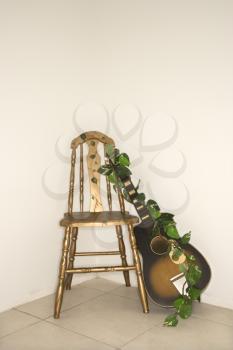Royalty Free Photo of a Guitar With Garland Leaning Against a Chair