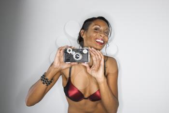 Royalty Free Photo of a Woman in Bra Holding up a Camera Smiling
