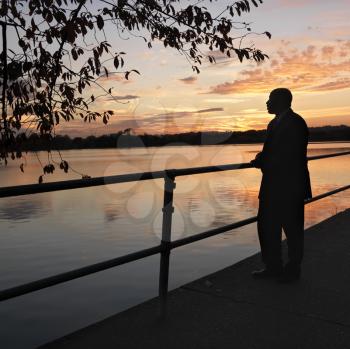 Royalty Free Photo of a Man Standing by the Water at Sunset in Washington, DC, USA