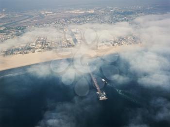 Aerial view of clouds covering beachfront and fishing pier in southern California.