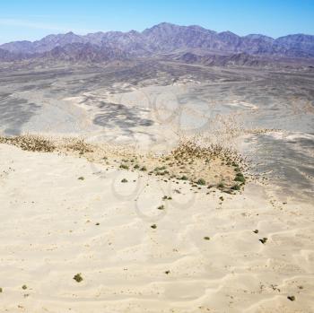 Aerial view of remote California desert with mountain range in background.