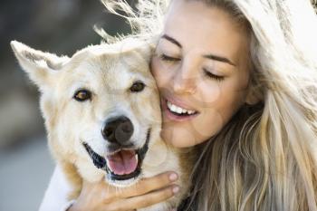 Royalty Free Photo of a Pretty Blond Woman Hugging a Dog and Smiling