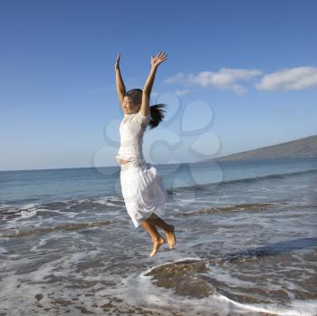 Royalty Free Photo of a Woman Jumping in the Air at the Shoreline