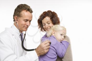 Royalty Free Photo of a Doctor Holding a Stethoscope to a Toddler's Back With Her Mother Watching