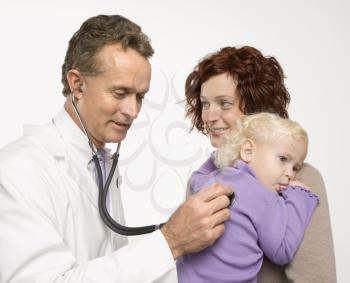 Royalty Free Photo of a Doctor Holding a Stethoscope to a Toddler's Back With Her Mother Watching